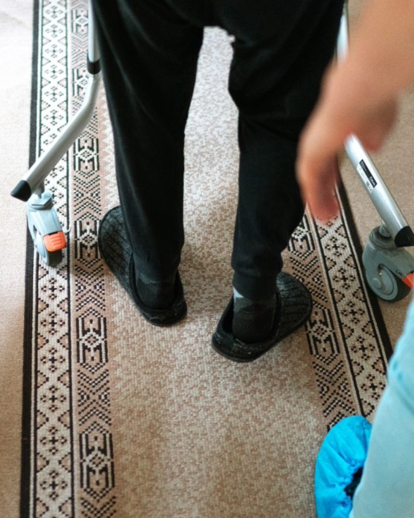 Cuidadora acompañando a un residente que utiliza andador durante una caminata matutina.