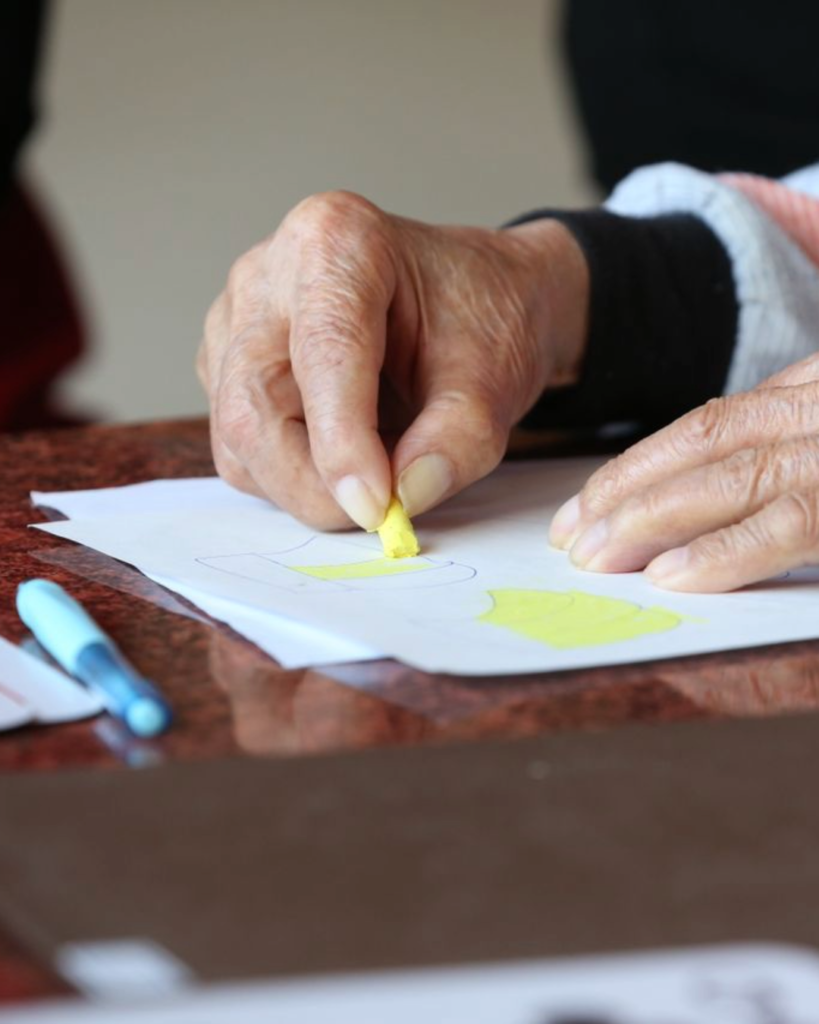 Adulta mayor residente realizando actividad de colorear un dibujo.